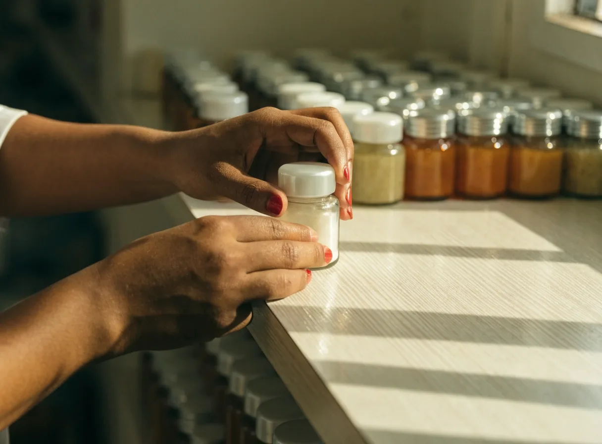 Hands placing a plain supplement jar onto a pearl laminate shelf lined with unmarked jars